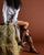 Person wearing cowboy boots sitting on a hay bale against a brown background