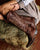 Brown cowboy boot with intricate design on a hay bale