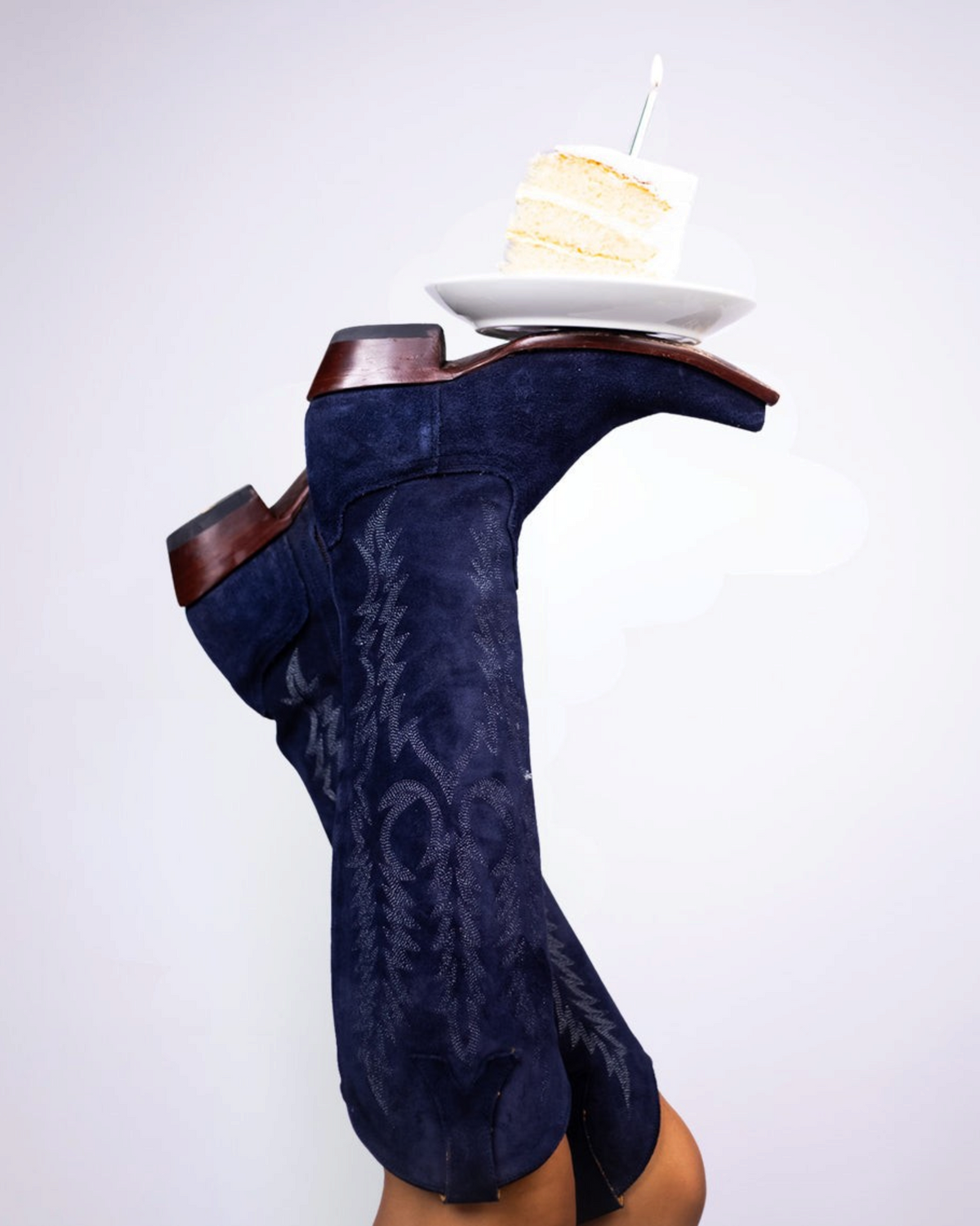 Old Gringo Boots Mayra navy blue suede western boots with intricate stitching and a cake plate balanced on the toe